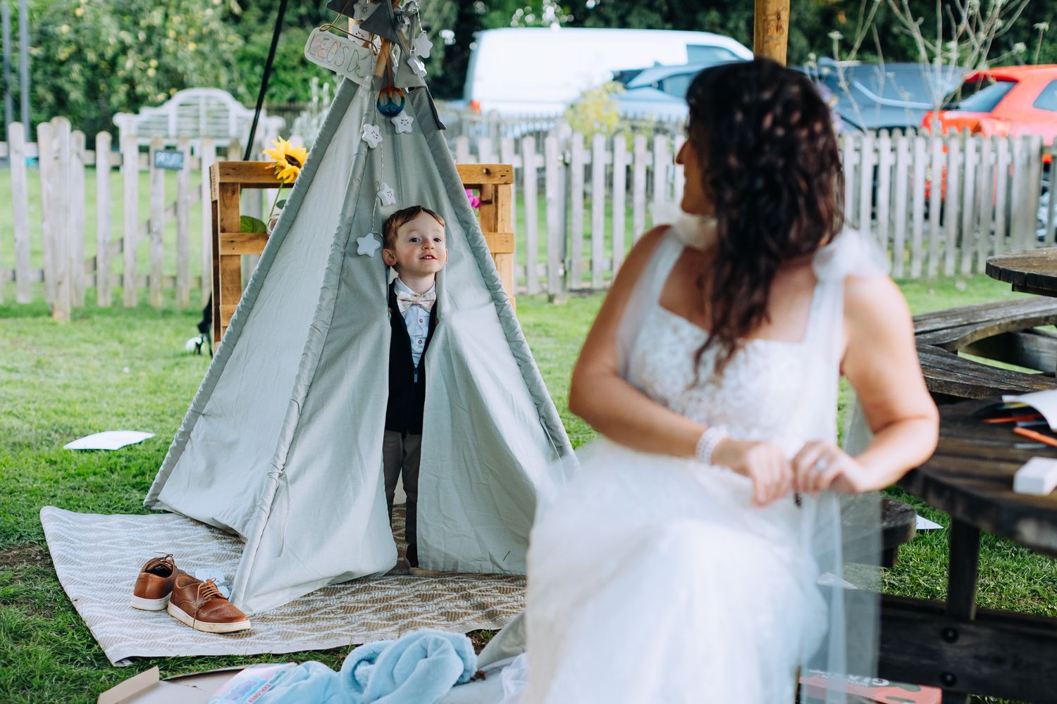 A wedding couple sits together at a rustic outdoor table during their garden reception celebration.