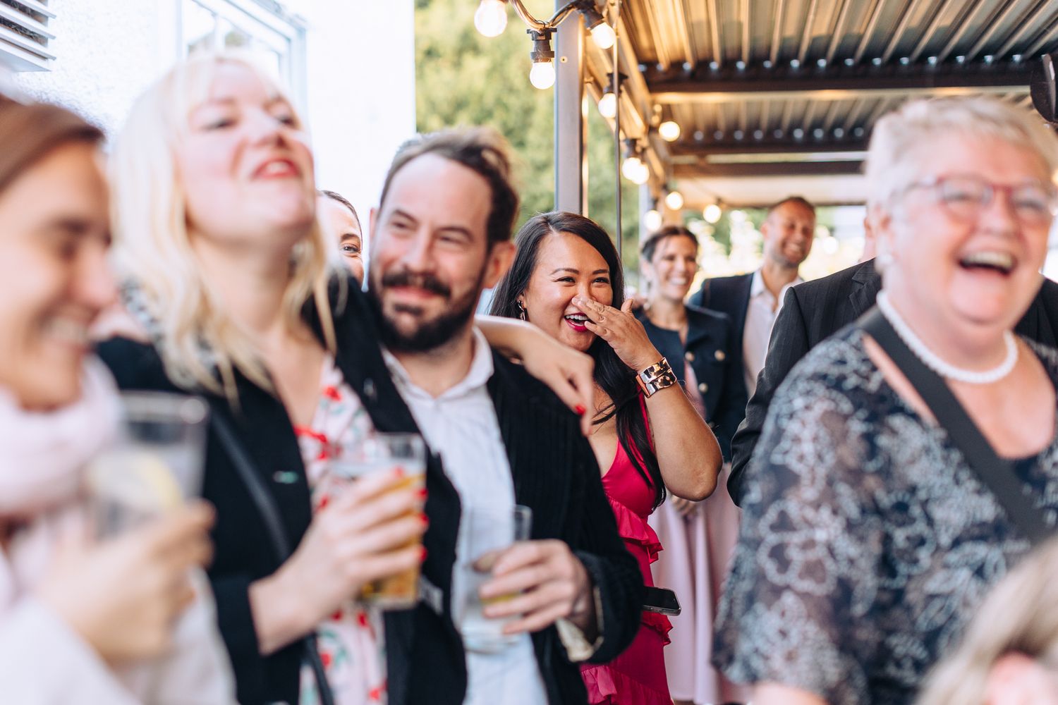Wedding guests laugh and celebrate together during an outdoor reception gathering.