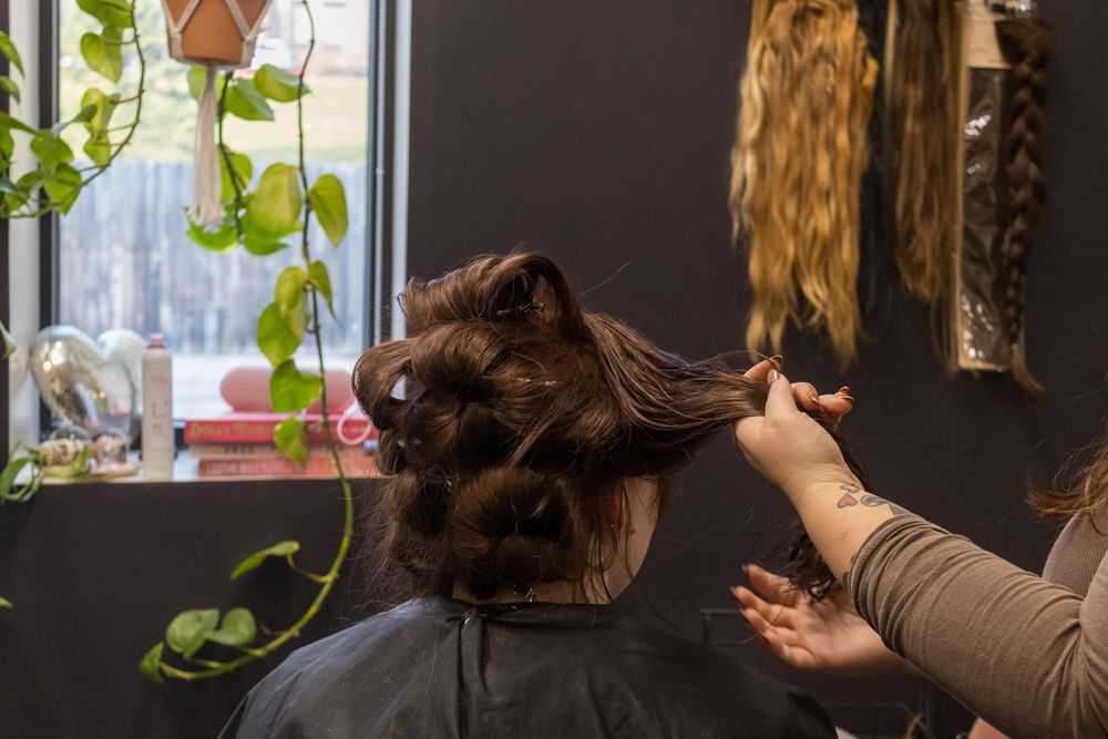 Hairstylist sectioning and styling client's hair in a professional salon setting.