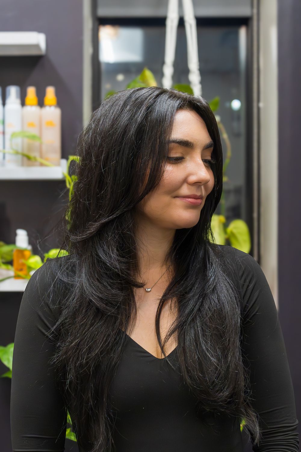 Long dark hair styled with soft layers and volume in a salon setting.
