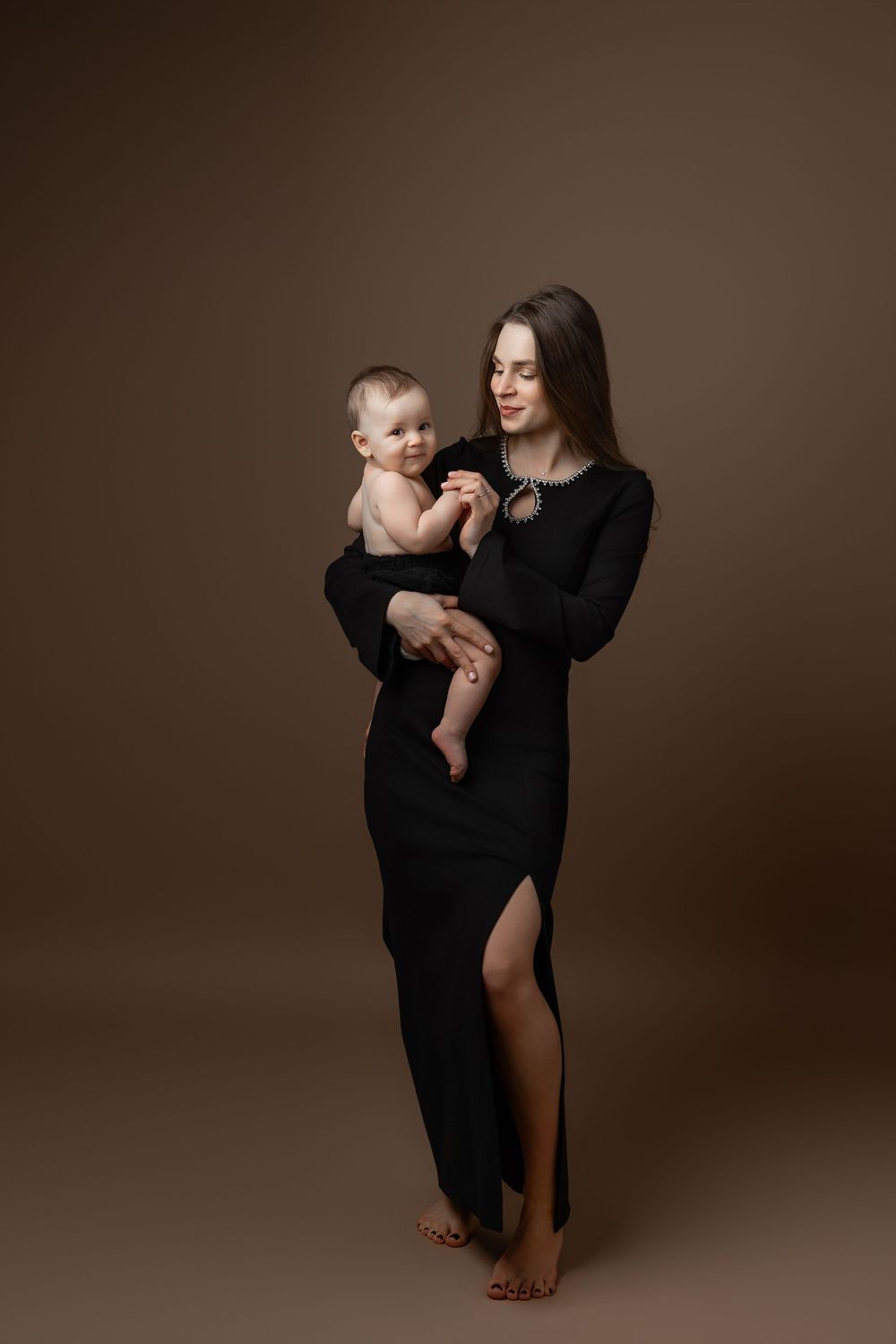 A tender moment captured in a series of photos showing a parent in black holding a baby against a brown backdrop.