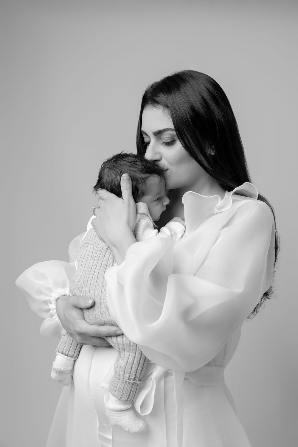 A sequence of black and white photographs showing a person in a white sweater hugging a plush toy.