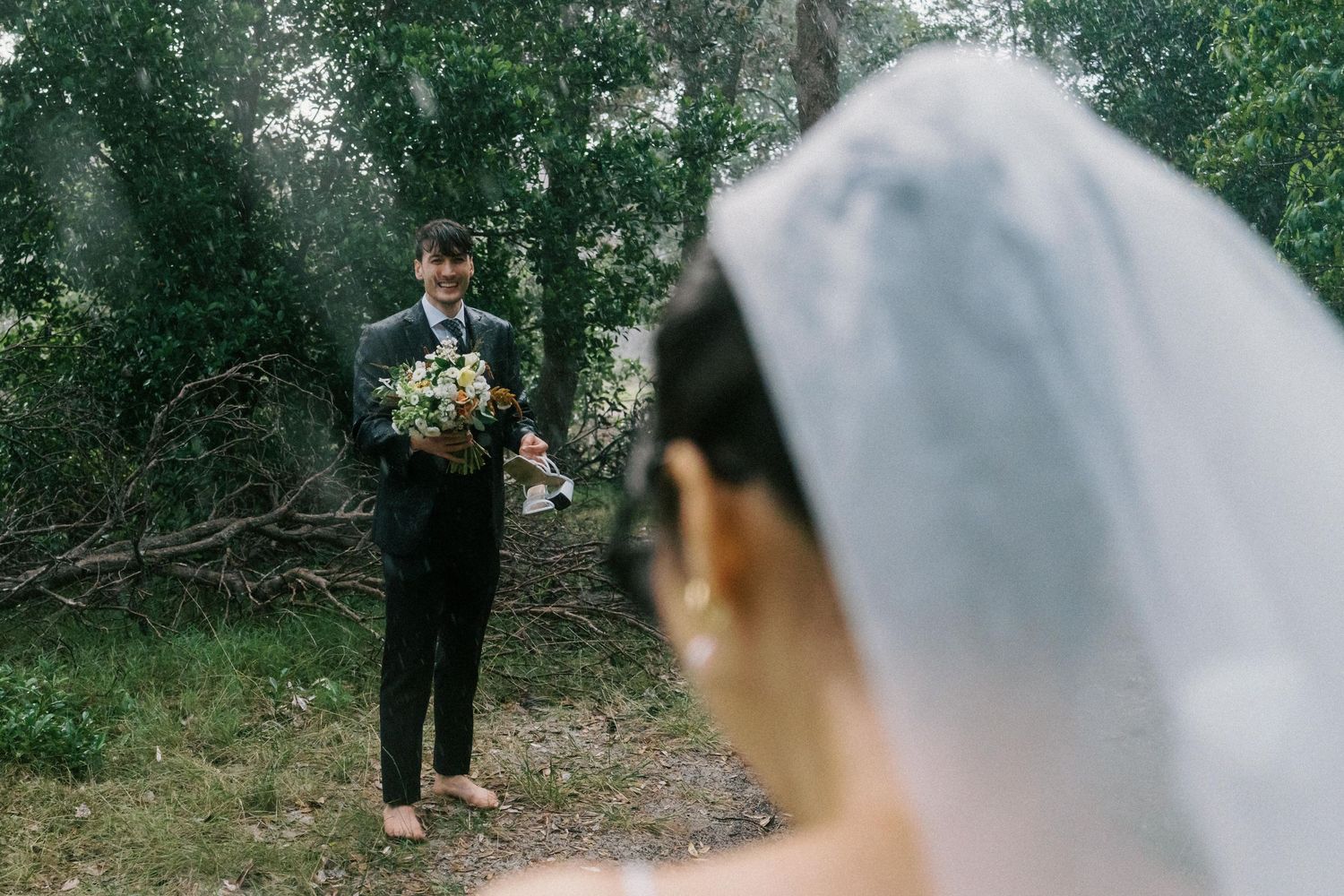 Romantic wedding couple walks hand in hand through a lush green garden path.