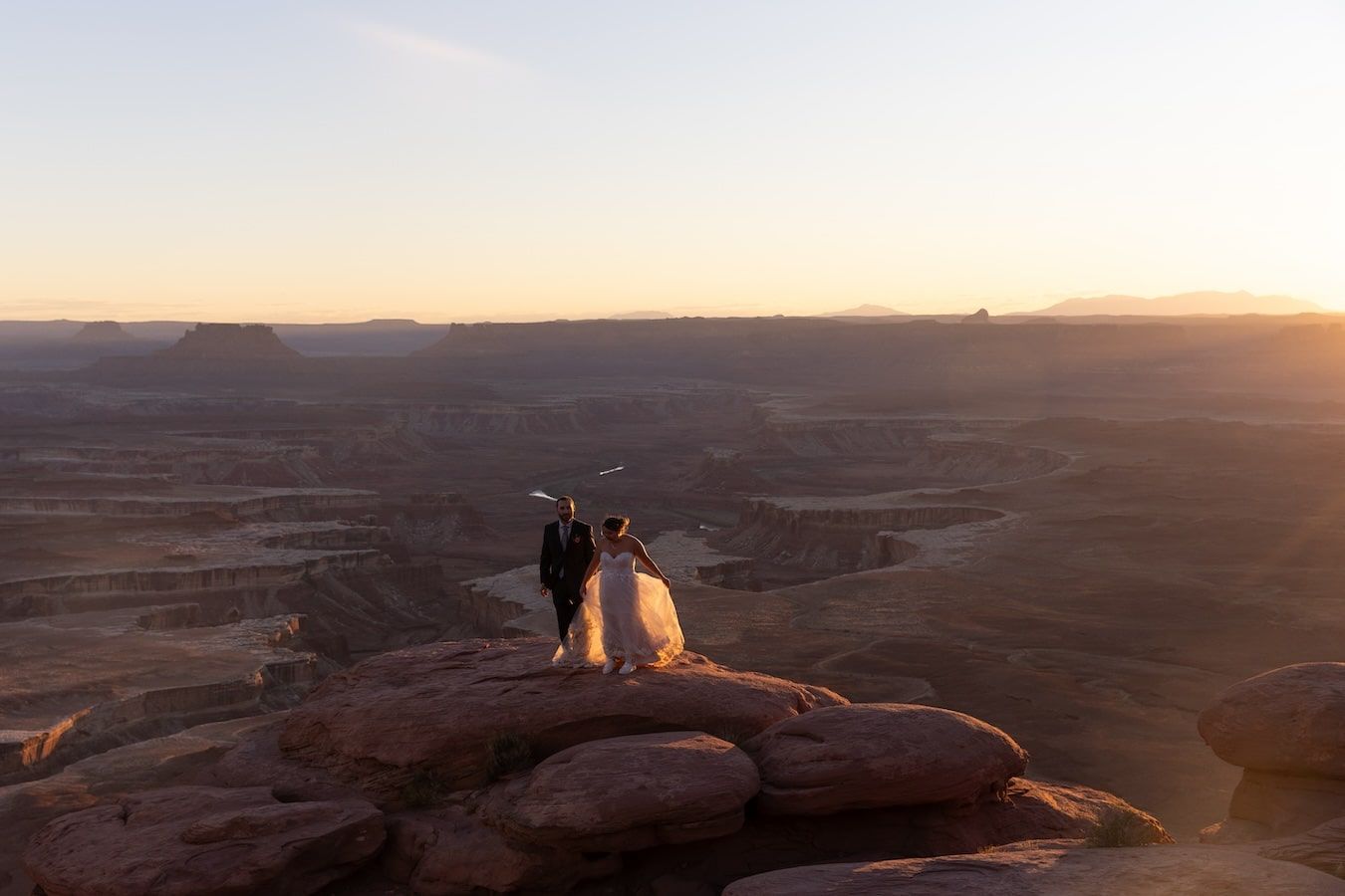 Silhouettes of people watching sunset from scenic overlook at Canyonlands National Park in Utah.