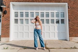 Senior session with jeans and white top against a brick wall with white garage doors in Perrysburg, Ohio.