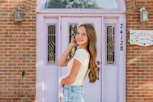 Classic pink doorway with arched window against red brick wall on a sunny day.
