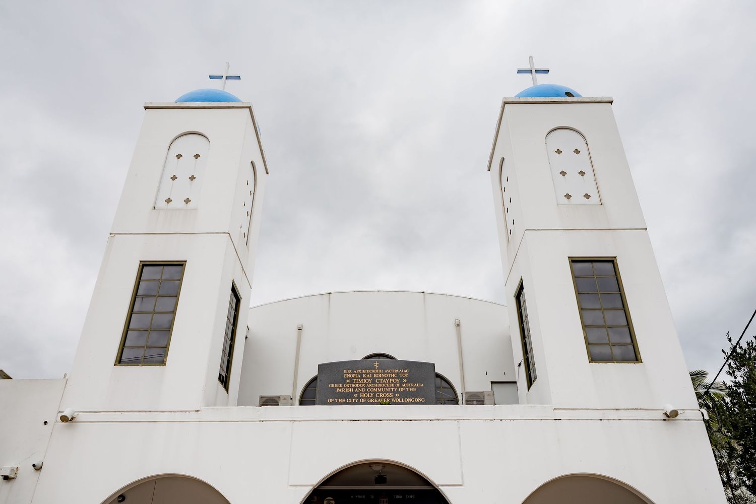 White church exterior with twin spires against cloudy sky.