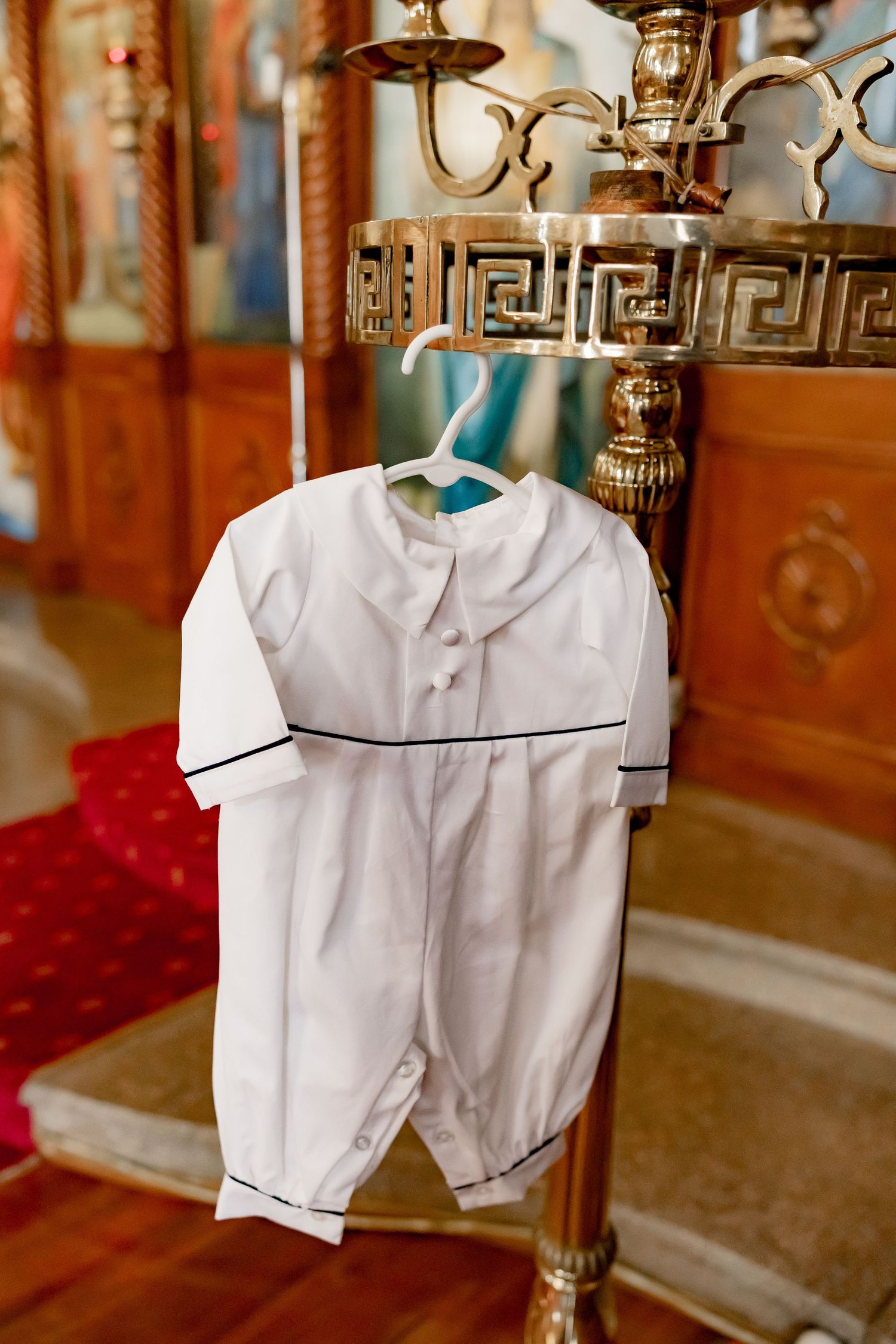 White baptismal outfit displayed on hangers in traditional style with peter pan collar.