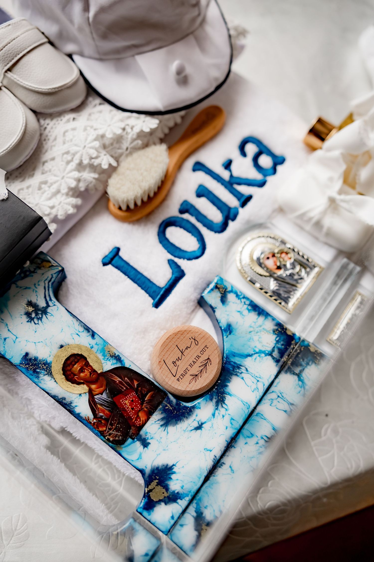 Baptism items including a white cloth with 'Louka' text and religious imagery in blue tones.