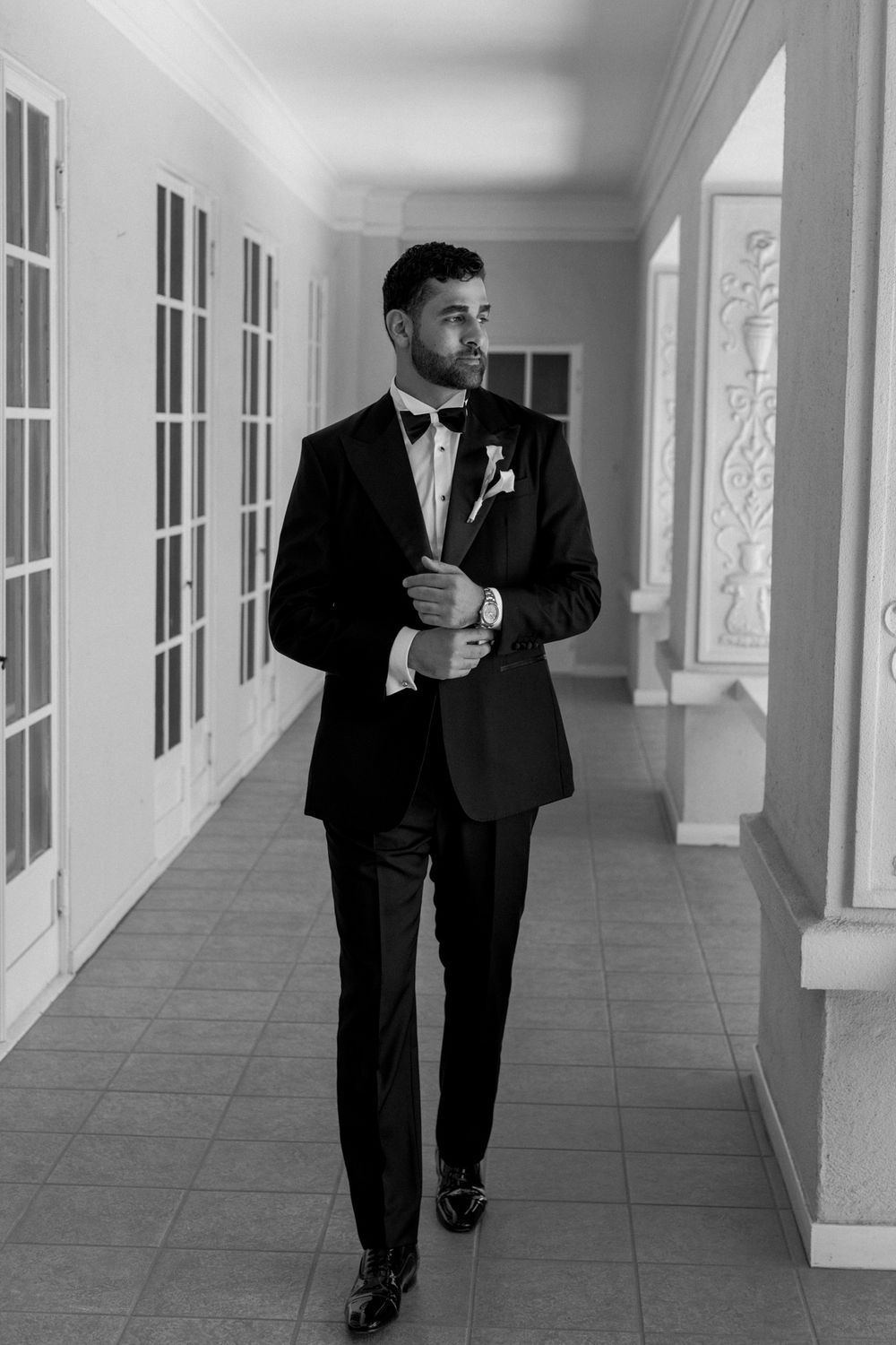 Classic black and white portrait in an elegant hallway with white French doors.