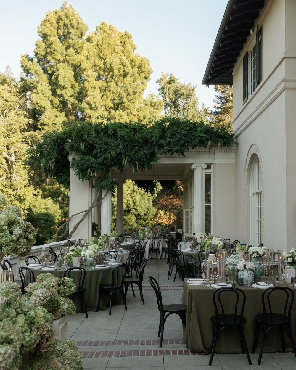 Outdoor wedding reception area with round tables set up on a Mediterranean-style patio.
