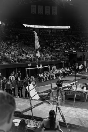 A sequence of vintage black and white photos showing a gymnast performing on the uneven parallel bars during competition.