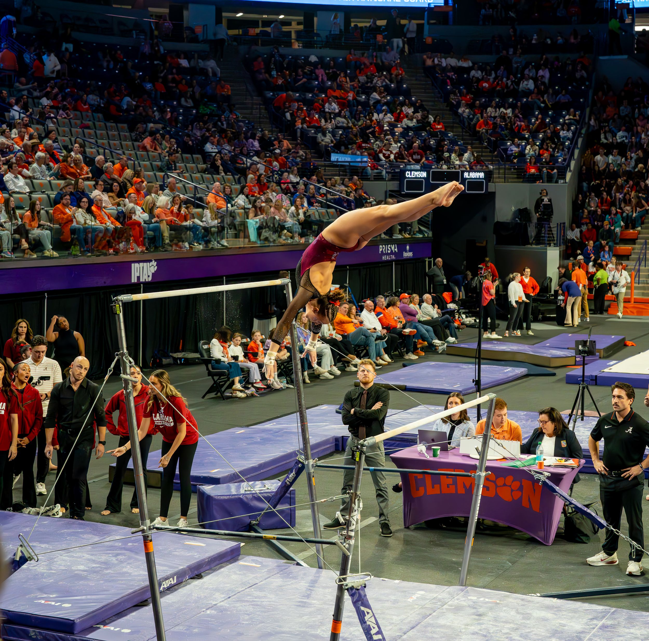 A gymnast performs a handstand routine on the parallel bars during a competition event.