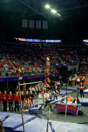Gymnast performs a routine on the uneven bars during a competitive gymnastics meet in an indoor arena.