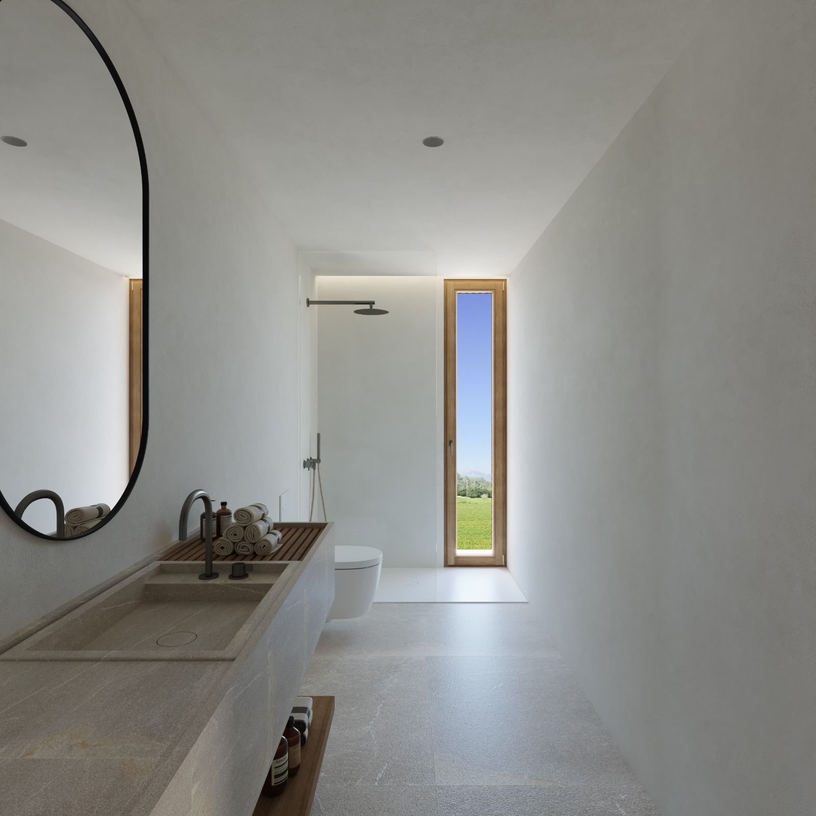 Modern minimalist bathroom with long concrete vanity, oval mirror, and tall narrow window offering view of green landscape.