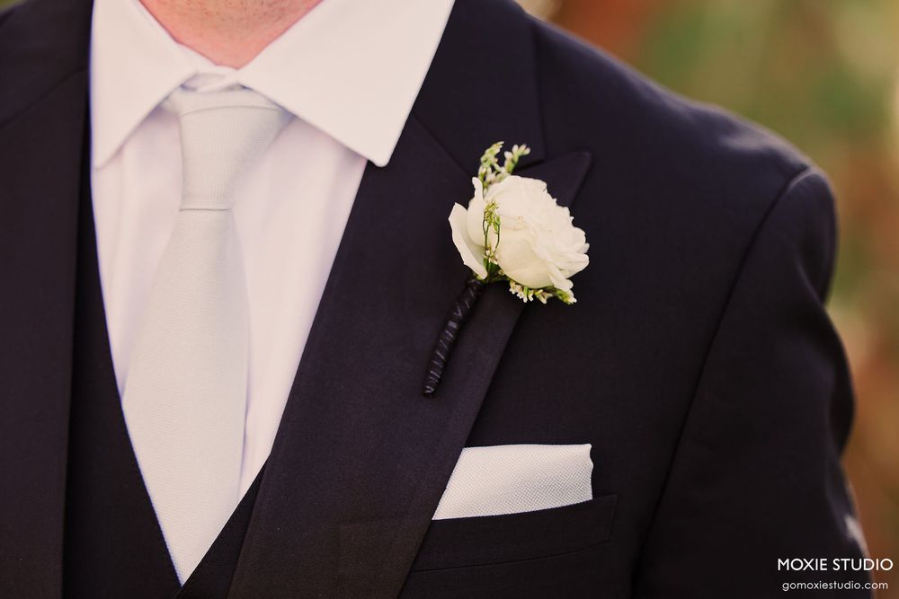 A close-up series of a groom's formal attire showing white shirt collar, navy suit jacket, and boutonniere details.