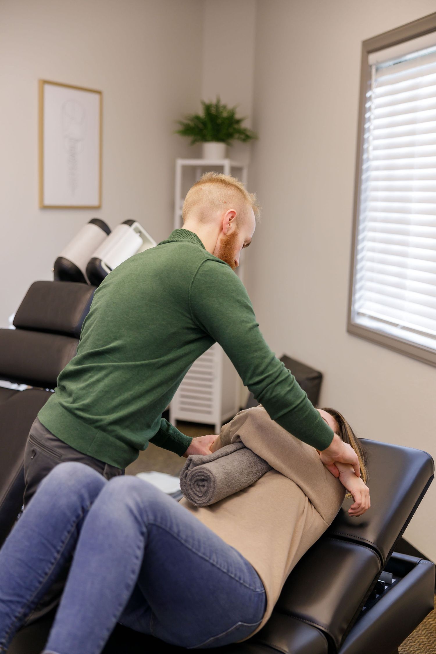 chiropractor branding photo in Sumner, WA wellness health man adjusting upper back of women cradling a towel between arms for treatment