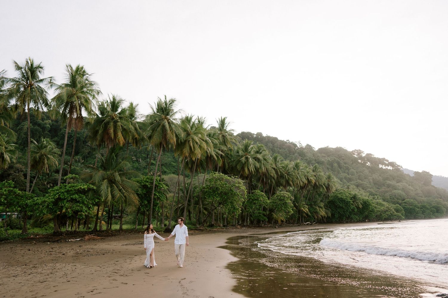Couple walking along Dominical Beach during a sunset elopement in Costa Rica.