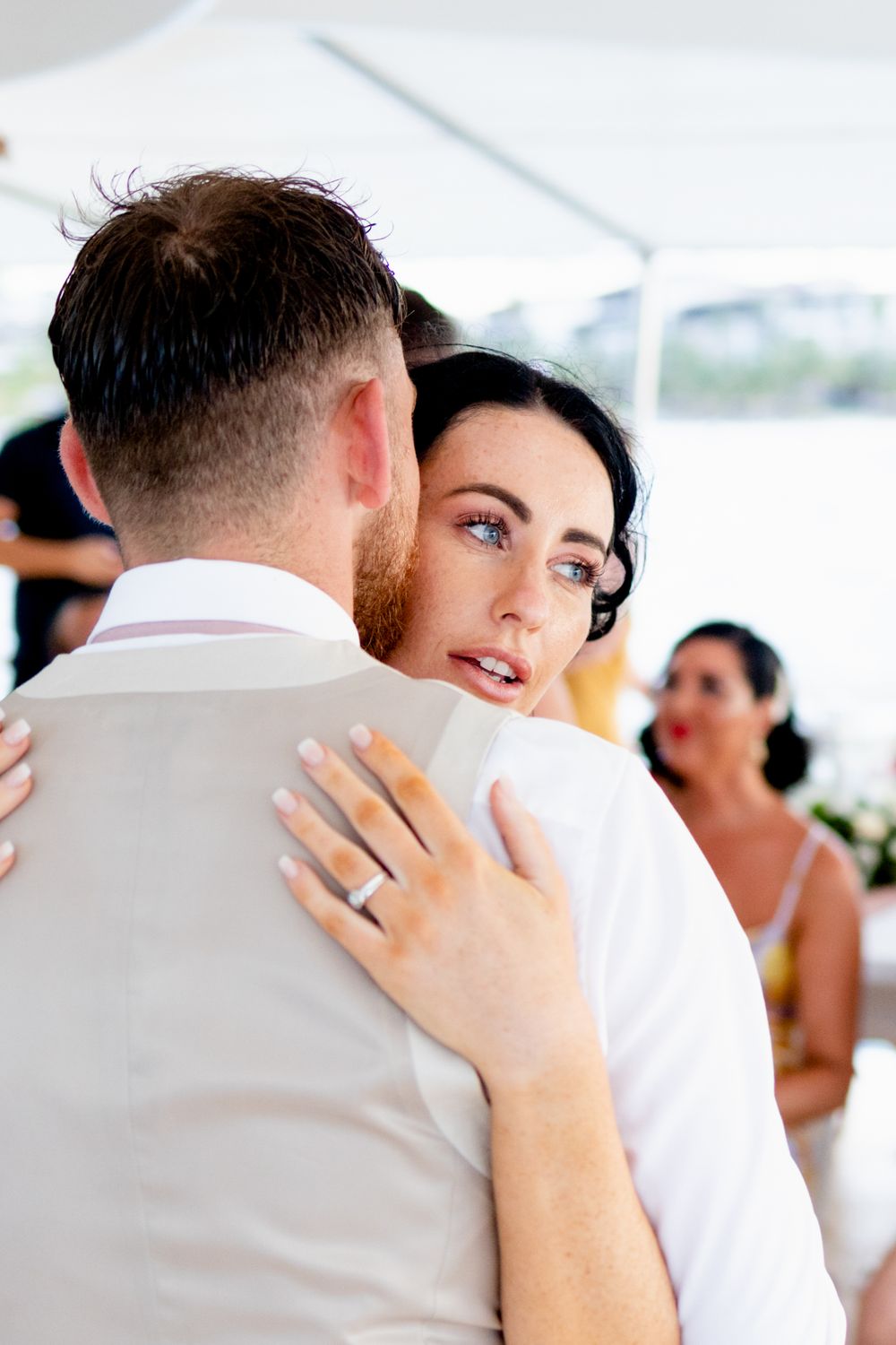 A tender embrace captured under a white tent during an intimate wedding celebration.