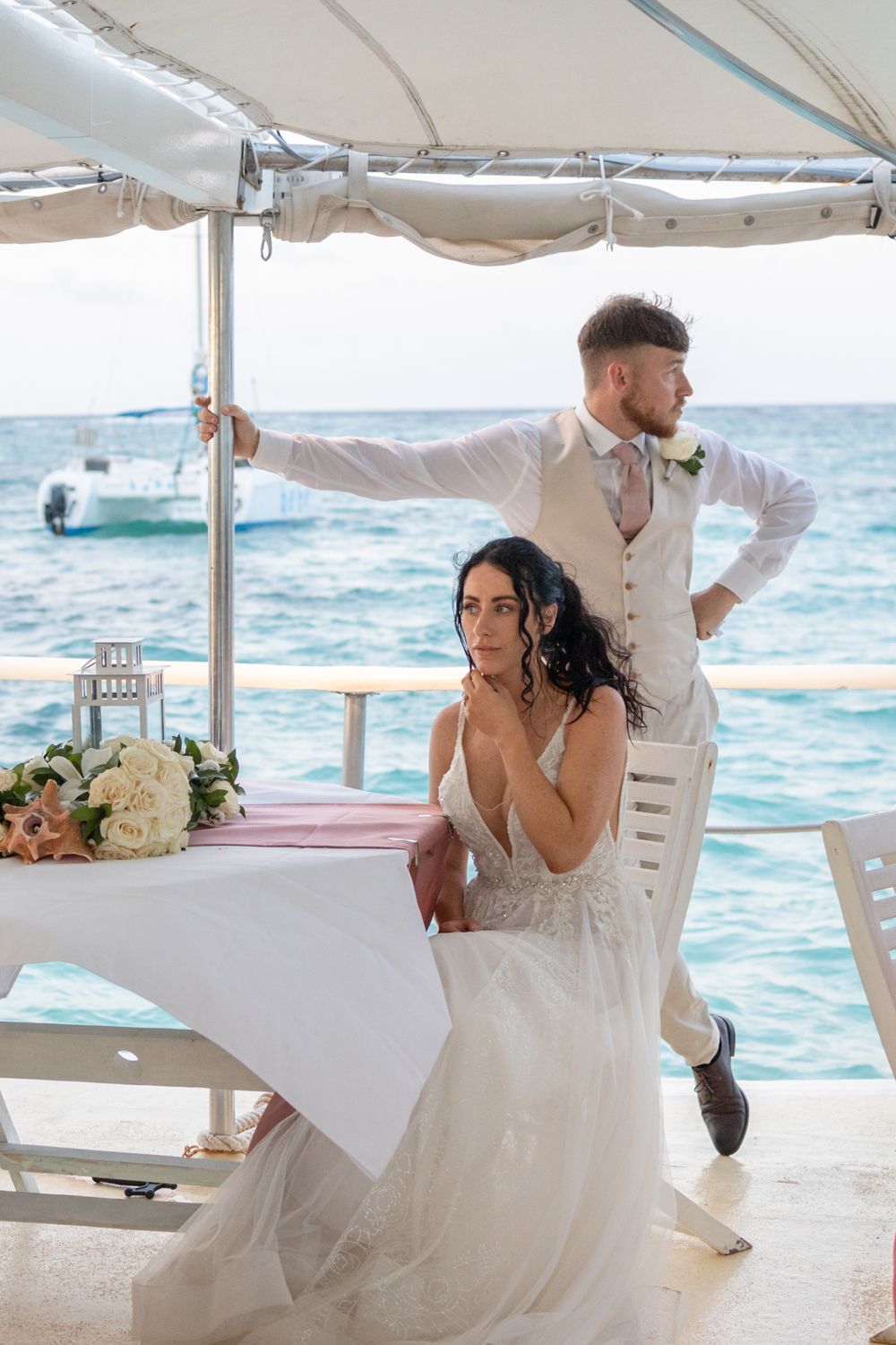 Couple dances romantically on a beachfront deck with ocean waves in the background.