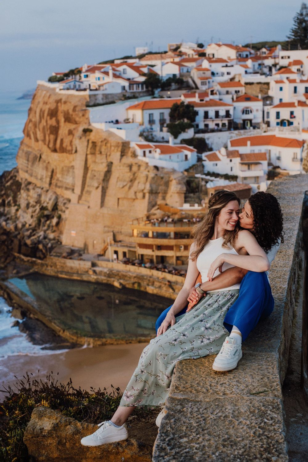 Scenic coastal view of white houses perched on cliffs overlooking the ocean in Azenhas do Mar, Portugal at sunset.