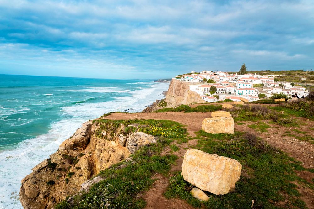 Scenic coastal cliffs and beaches along Portugal's rugged coastline with white buildings perched on the edge.