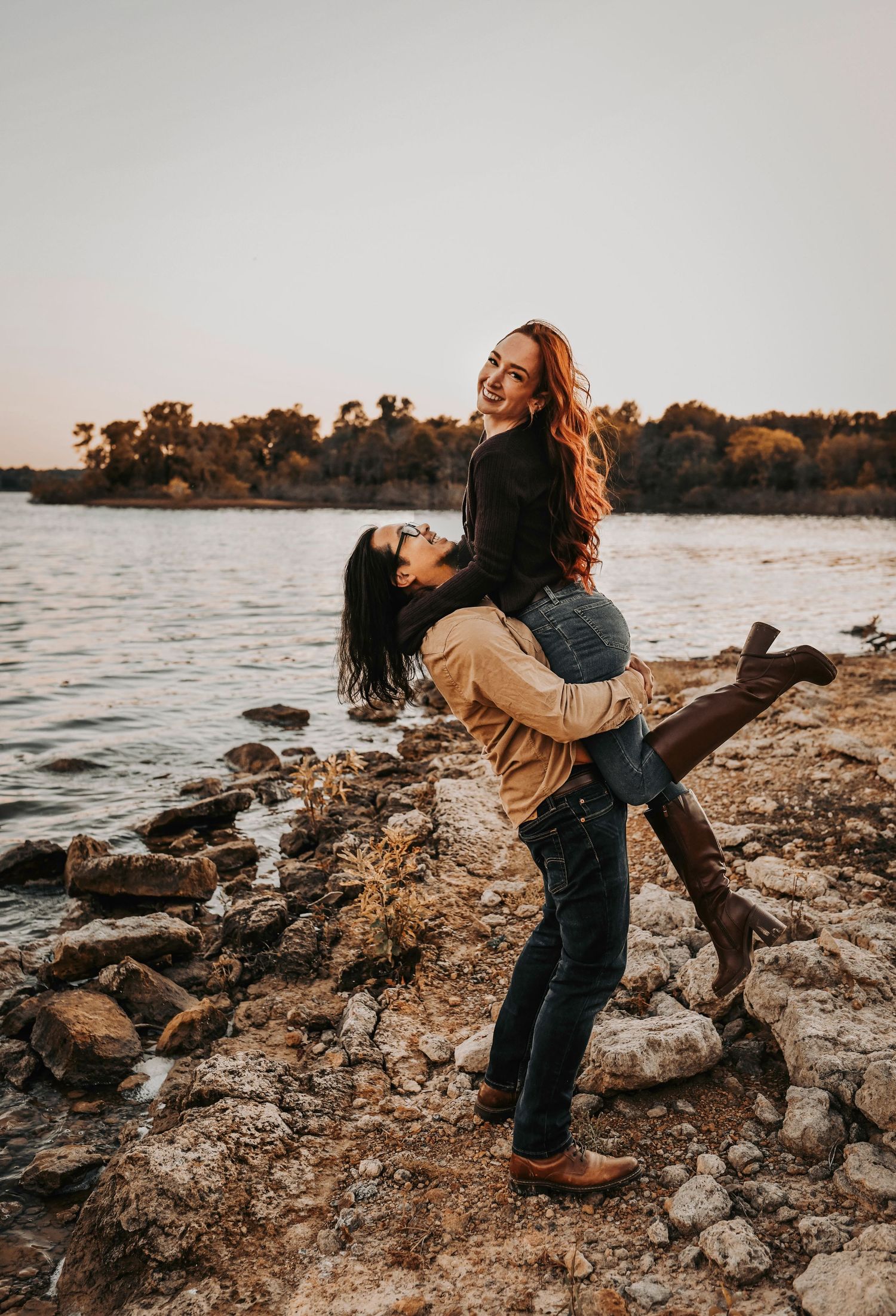 candid moment between a couple as he lifts her up and she smiles at the camera