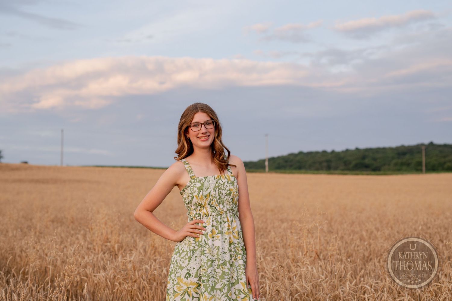Someone in a floral sundress poses confidently in wheat field at dusk.
