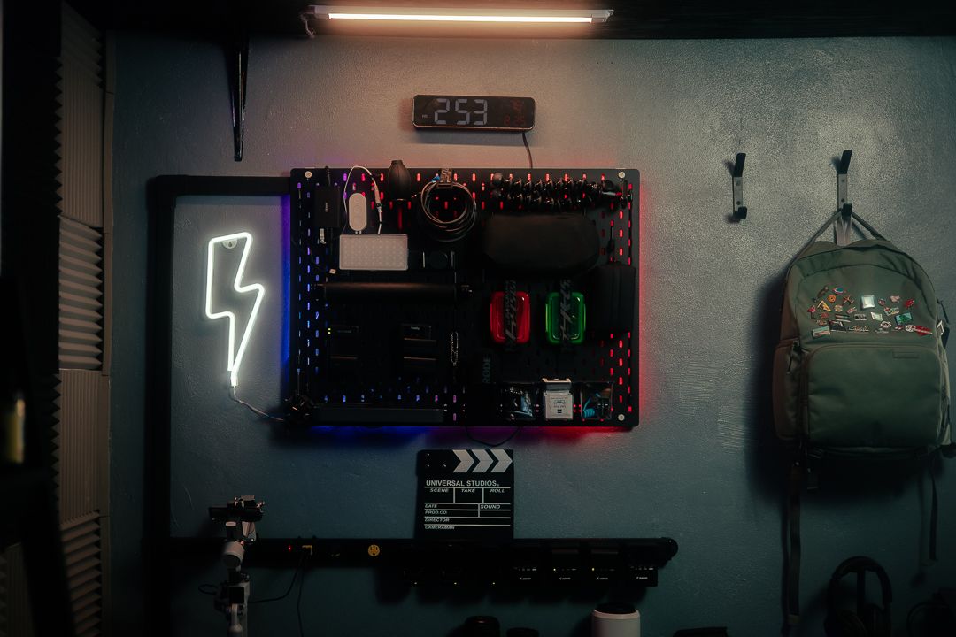 Mannyportraits Miami creative studio wall setup with neon lightning sign, camera gear, RODE equipment, and cinematic workspace decor.