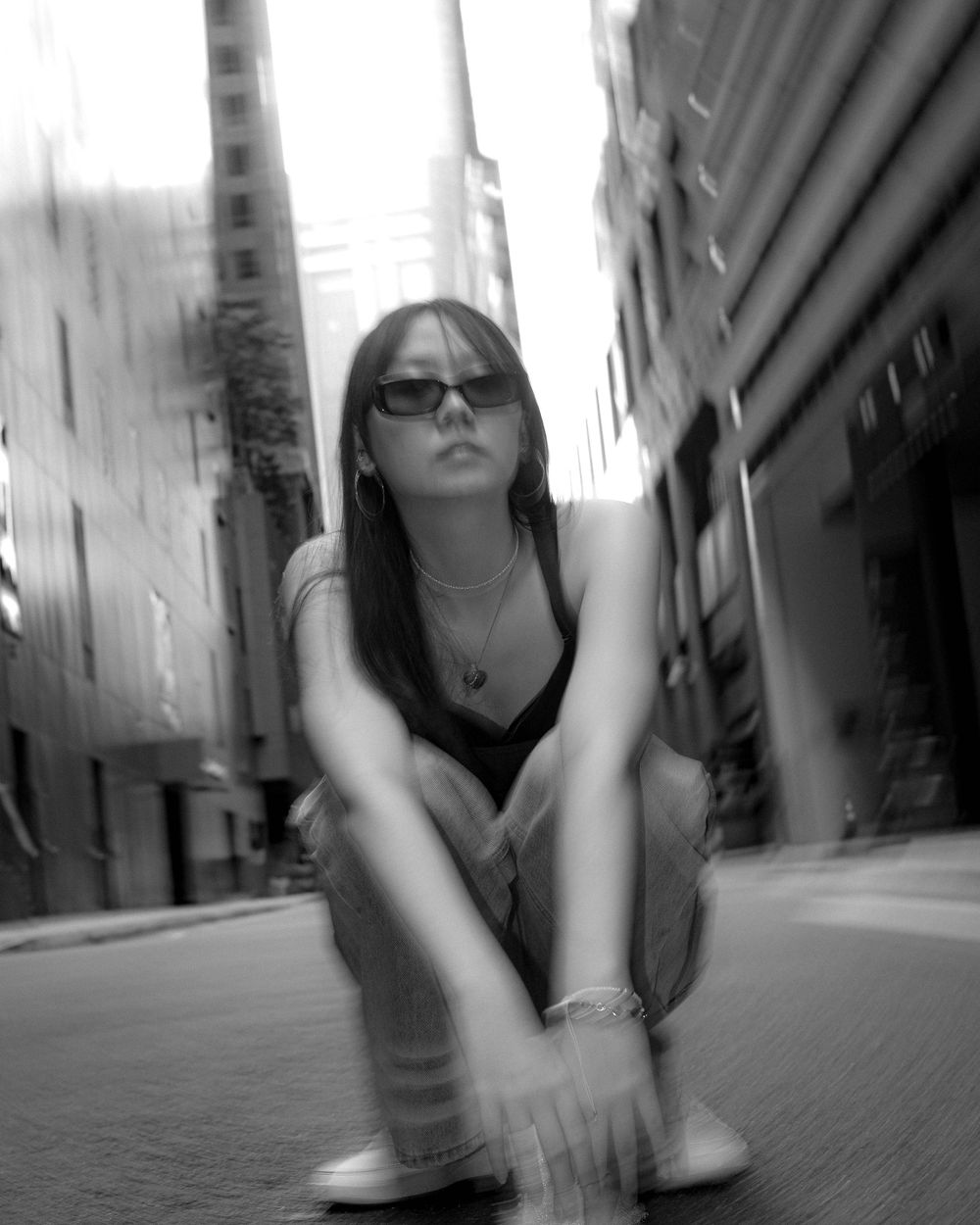 Black and white urban portrait with dramatic city architecture in background.