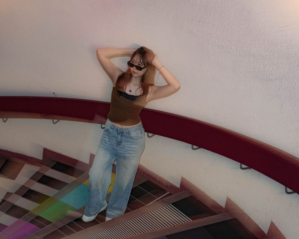 A stylish pose on spiral stairs with light effects creating a dreamy atmosphere.