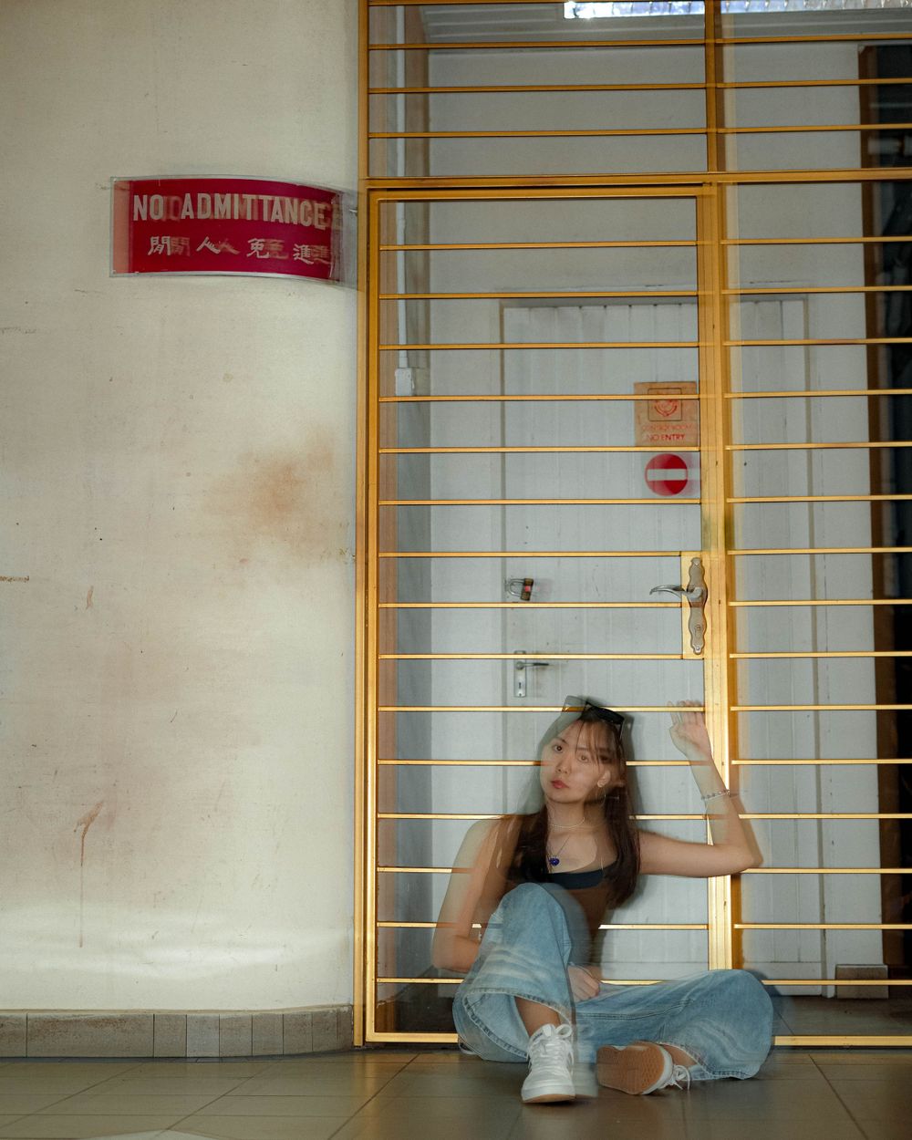 A relaxed pose by yellow metal bars with a 'No Admittance' sign visible.
