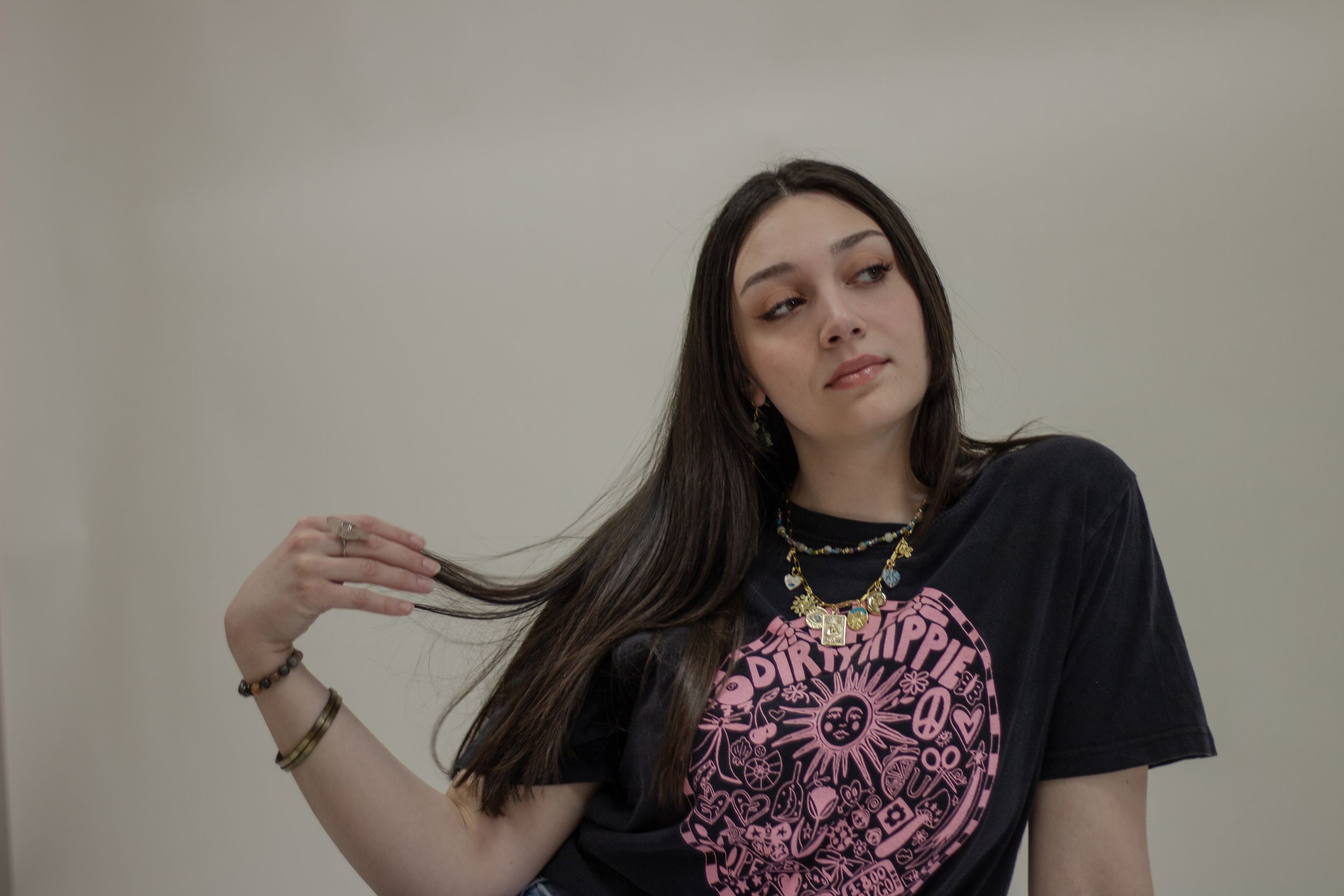 A person wearing a black t-shirt with pink graphics poses in a  against a light background during a company branding photoshoot.