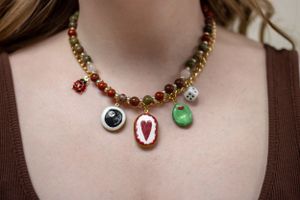 Close-up view of delicate gold jewelry including rings and earrings worn with a brown top.