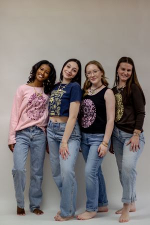 A group of friends pose together outdoors in coordinated dresses and outfits for a company branding session at a photography studio.