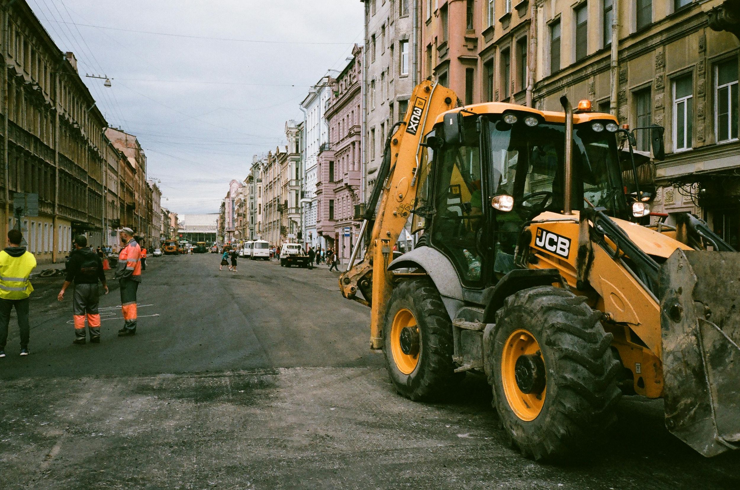 Construction equipment working on road repairs in an urban street setting.