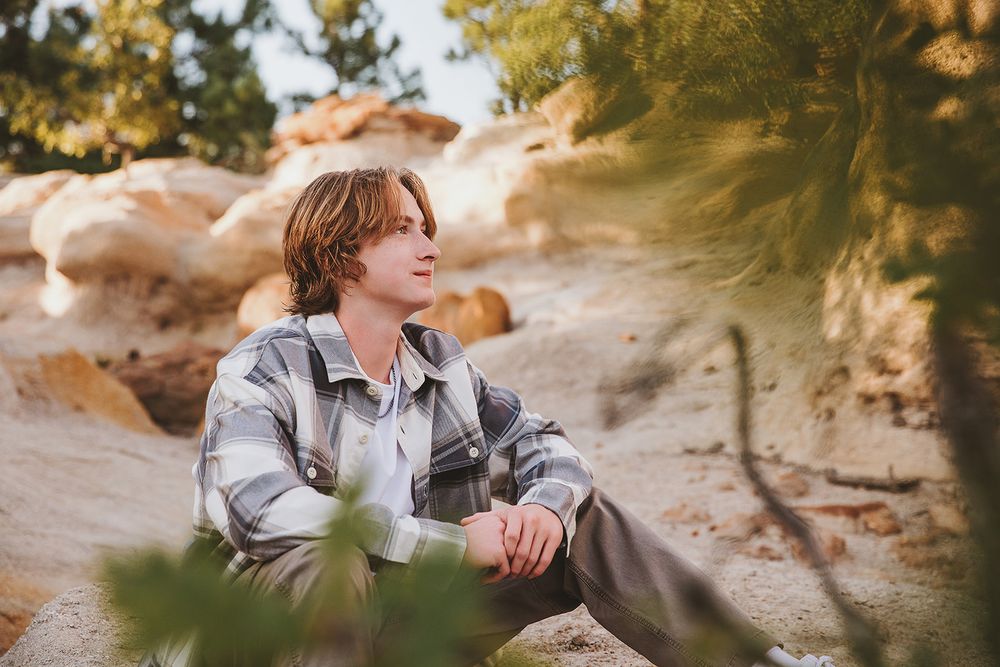 Natural outdoor portrait among desert rock formations and pine trees.