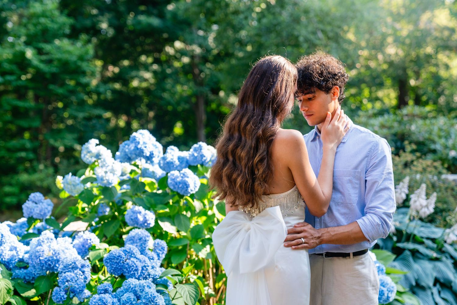Romantic moment between couple among blooming blue hydrangea flowers in garden setting.