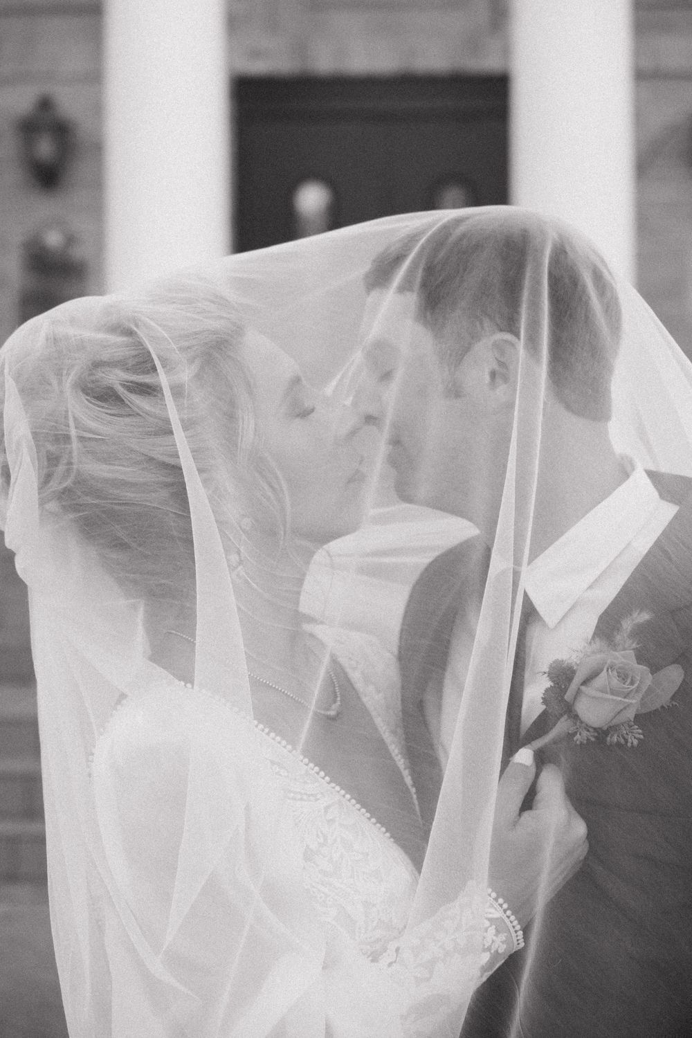 A row of delicate white wedding veils flowing in a soft breeze creates an ethereal effect against a light background.
