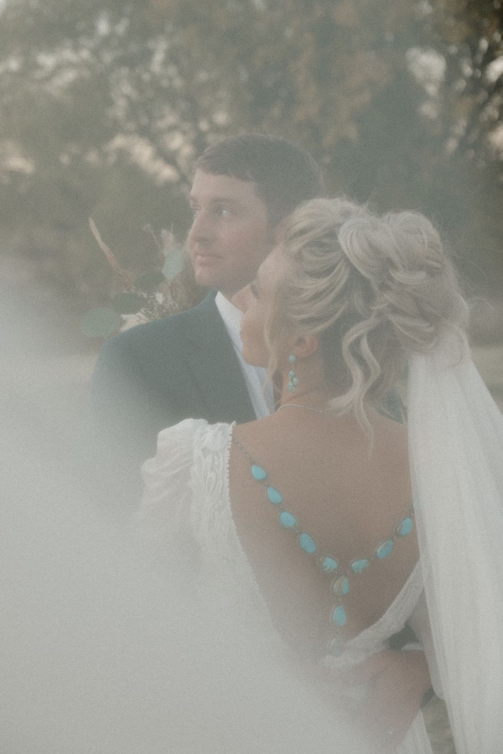 A dreamy wedding portrait series shows a couple in soft focus with the bride wearing a turquoise necklace and veil.