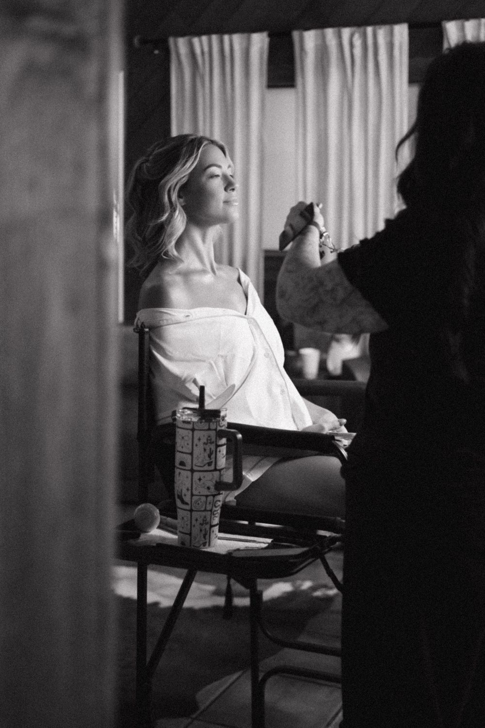A black and white photo series showing a woman in white clothing sitting at a desk by a window.