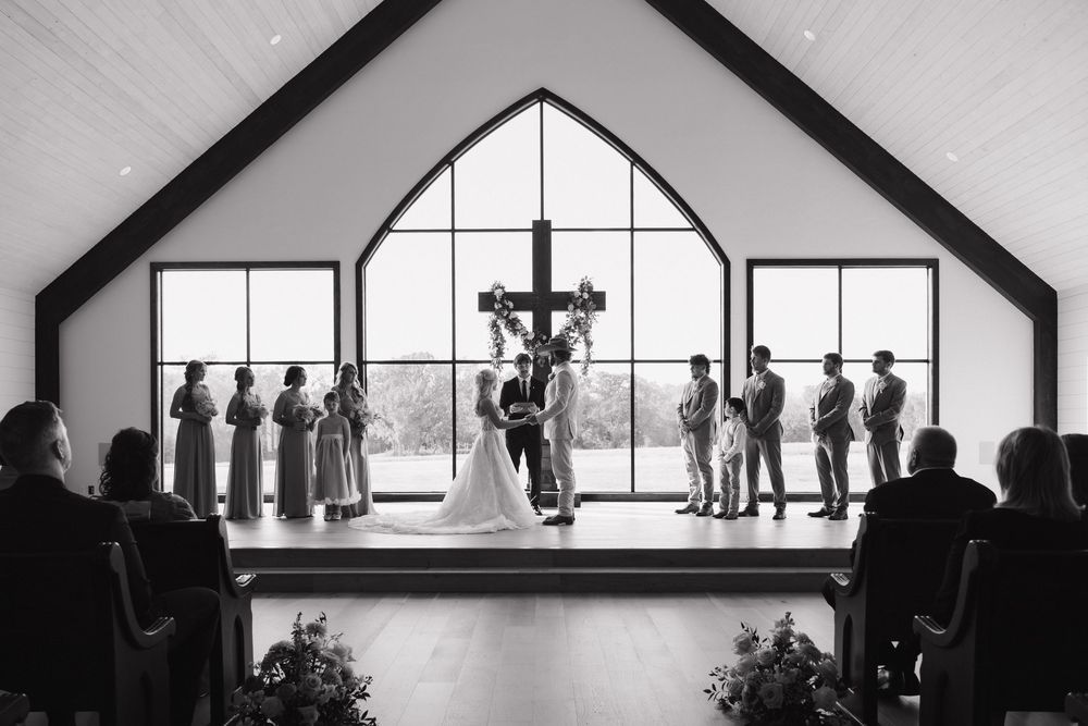 Silhouettes of people standing by large windows in an art gallery or museum space create a dramatic architectural scene.
