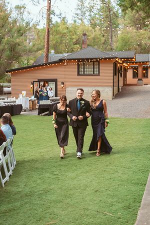 An outdoor reception area with string lights decorating a tan colored venue building and manicured lawn.