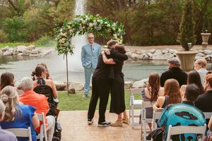 A group enjoying an outdoor wedding ceremony in a scenic forest setting near a waterfall in the springtime.