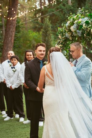 Outdoor wedding celebration with string lights and pine trees creating a romantic atmosphere.