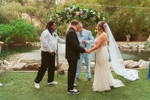 Wedding participants move across a grassy lawn during an outdoor ceremony with mountains in the background.