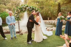 Garden wedding ceremony with decorative floral arrangements and natural woodland backdrop.