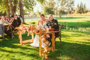 Outdoor wedding reception table decorated with autumn colors and floral arrangements in a sunny garden setting.