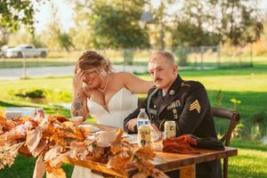Couple shares a candid moment at their outdoor wedding reception with autumn decorations on their dining table.