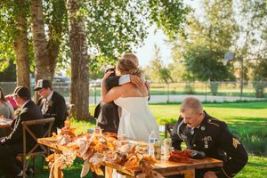 Emotional embrace at wedding reception table decorated with autumn florals and rustic elements.